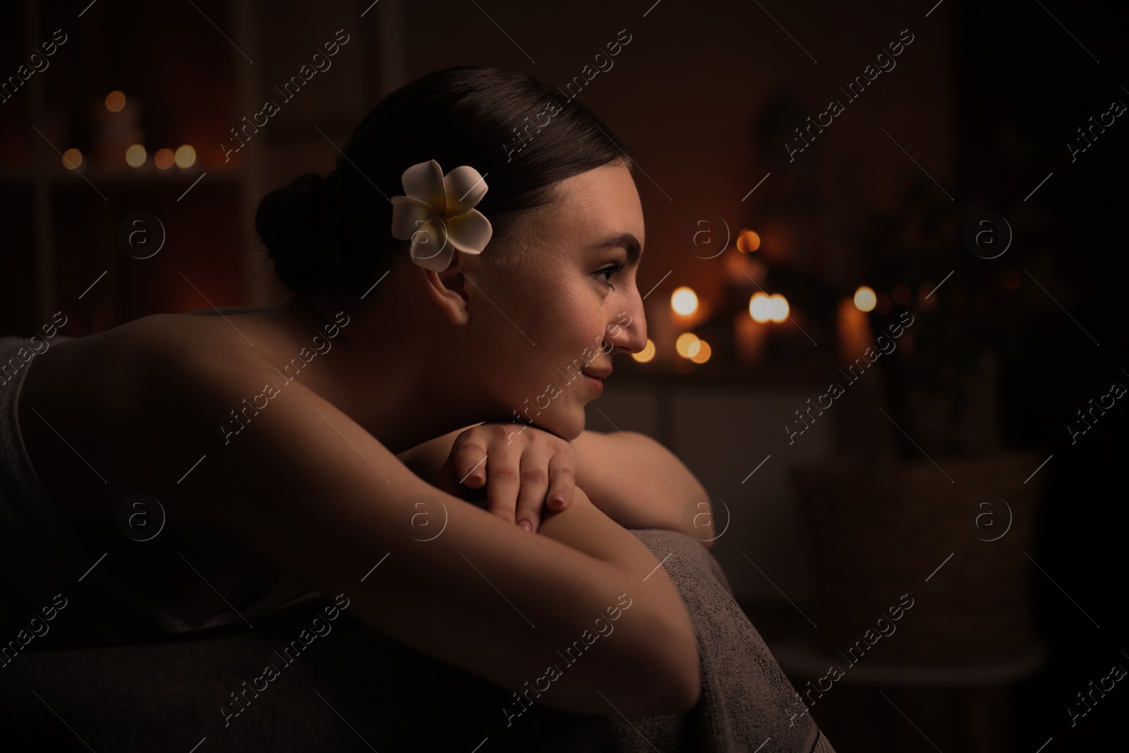 Image of Beautiful young woman lying on massage table in salon, space for text