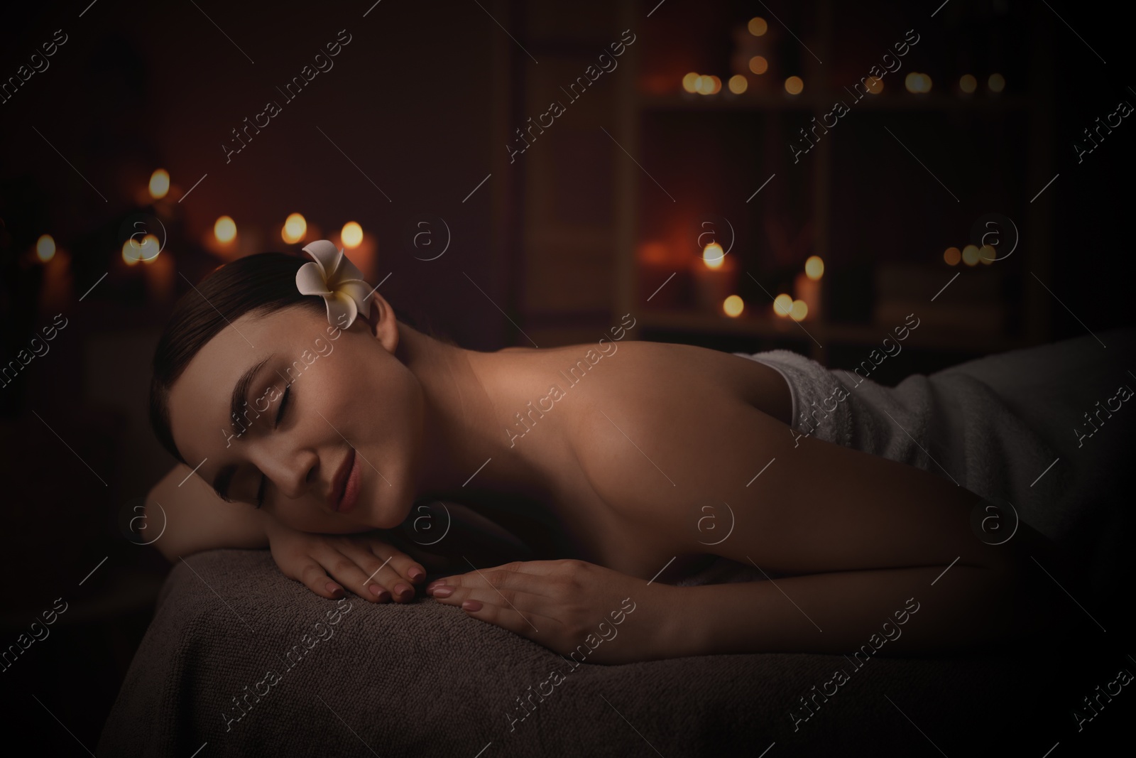 Image of Beautiful young woman lying on massage table in salon