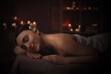 Image of Beautiful young woman lying on massage table in salon