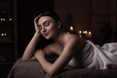 Image of Beautiful young woman lying on massage table in salon