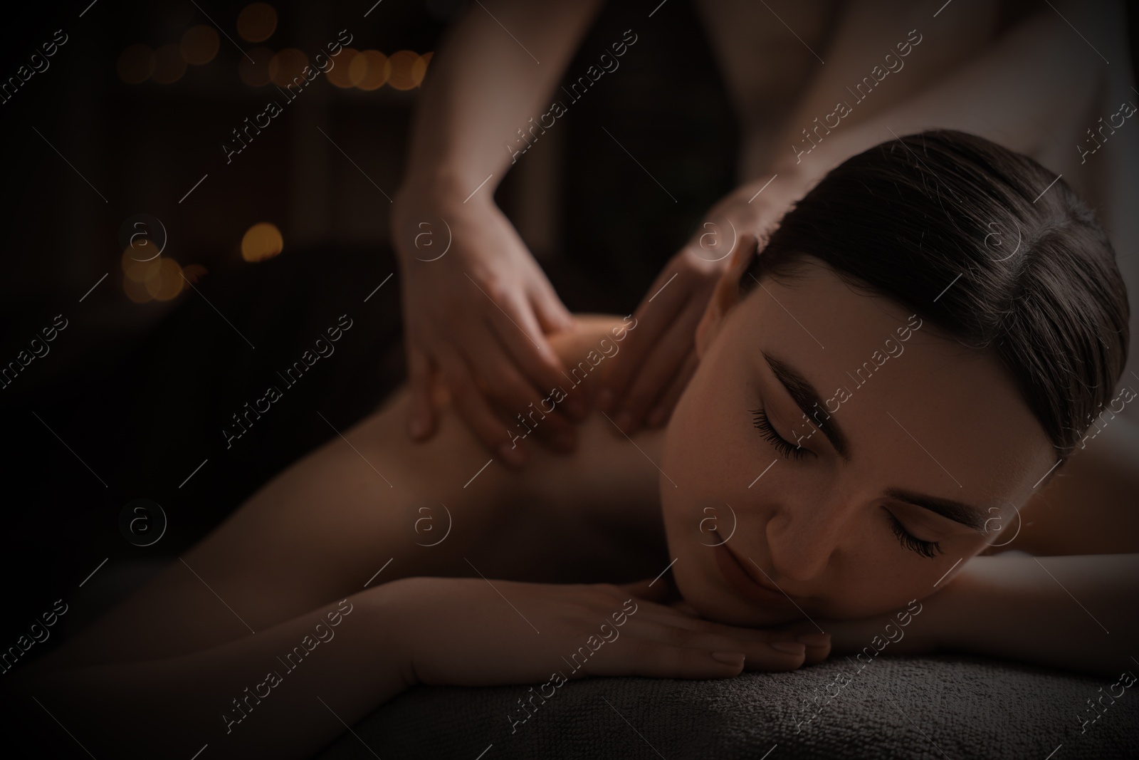 Image of Beautiful young woman lying on table during massage in salon