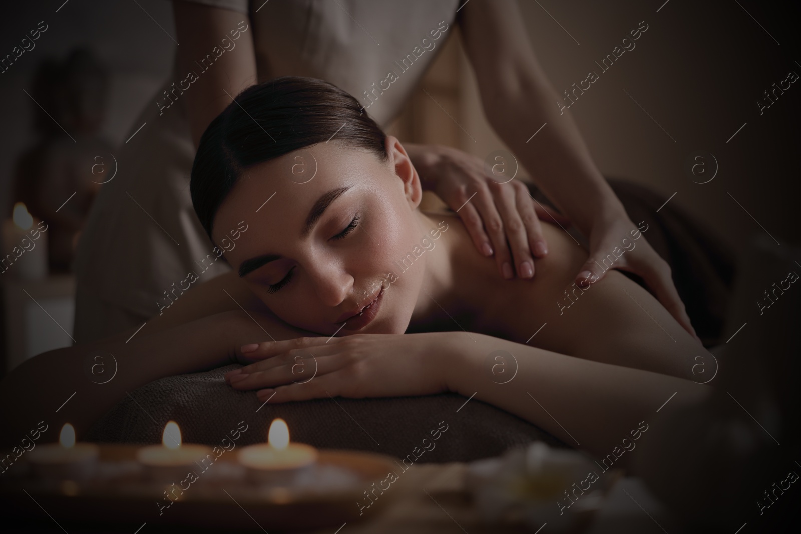 Image of Beautiful young woman lying on table during massage in salon