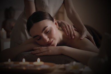 Beautiful young woman lying on table during massage in salon