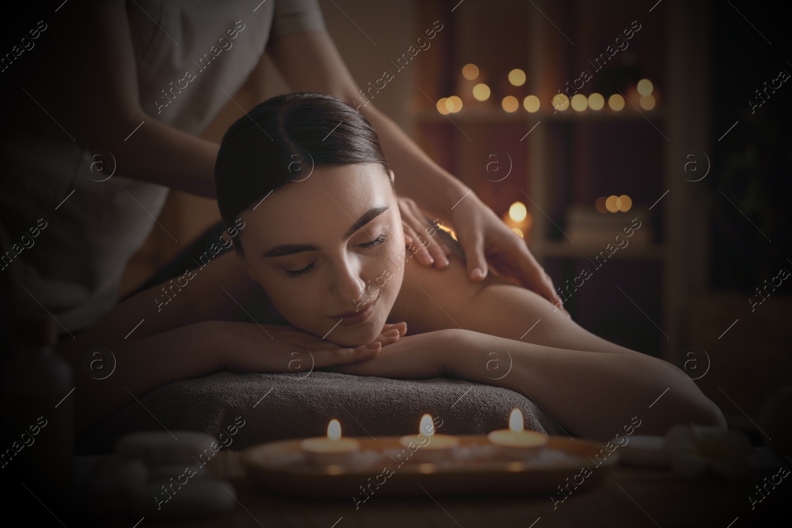 Image of Beautiful young woman lying on table during massage in salon