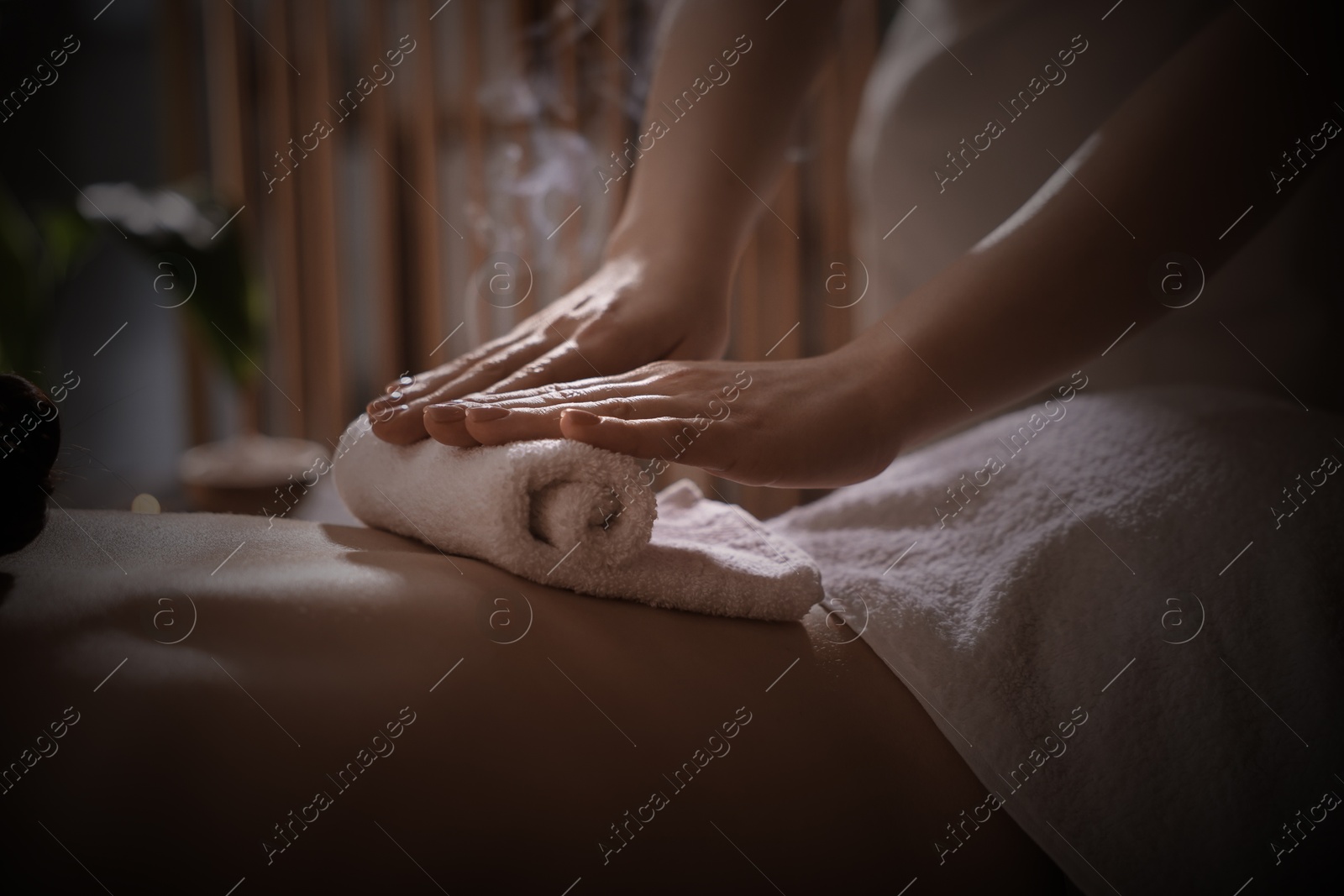 Image of Beautiful young woman lying on table during hot towel massage in salon, closeup