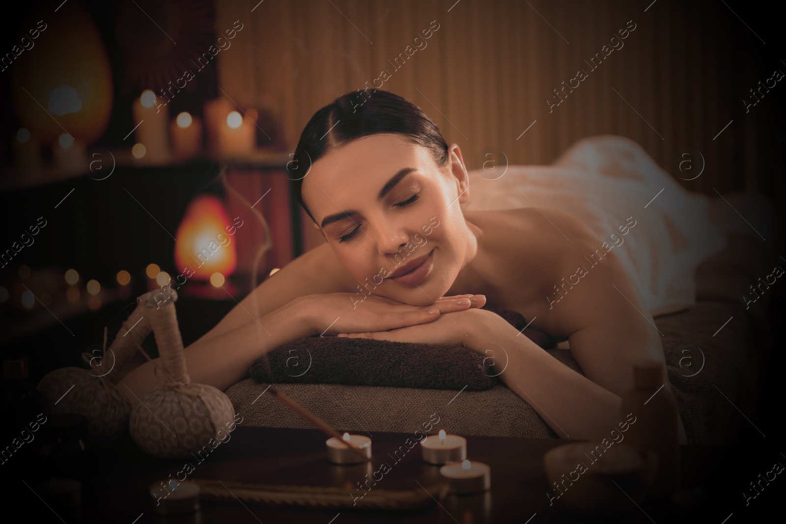 Image of Beautiful young woman lying on massage table in salon