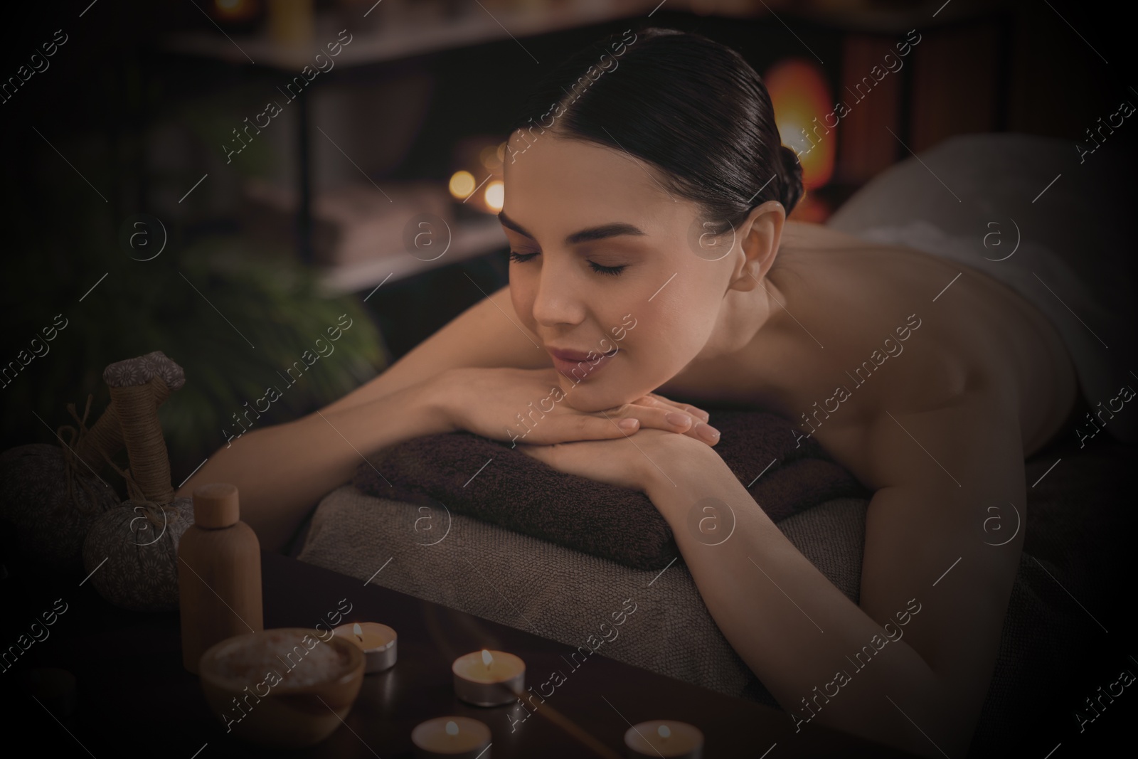 Image of Beautiful young woman lying on massage table in salon