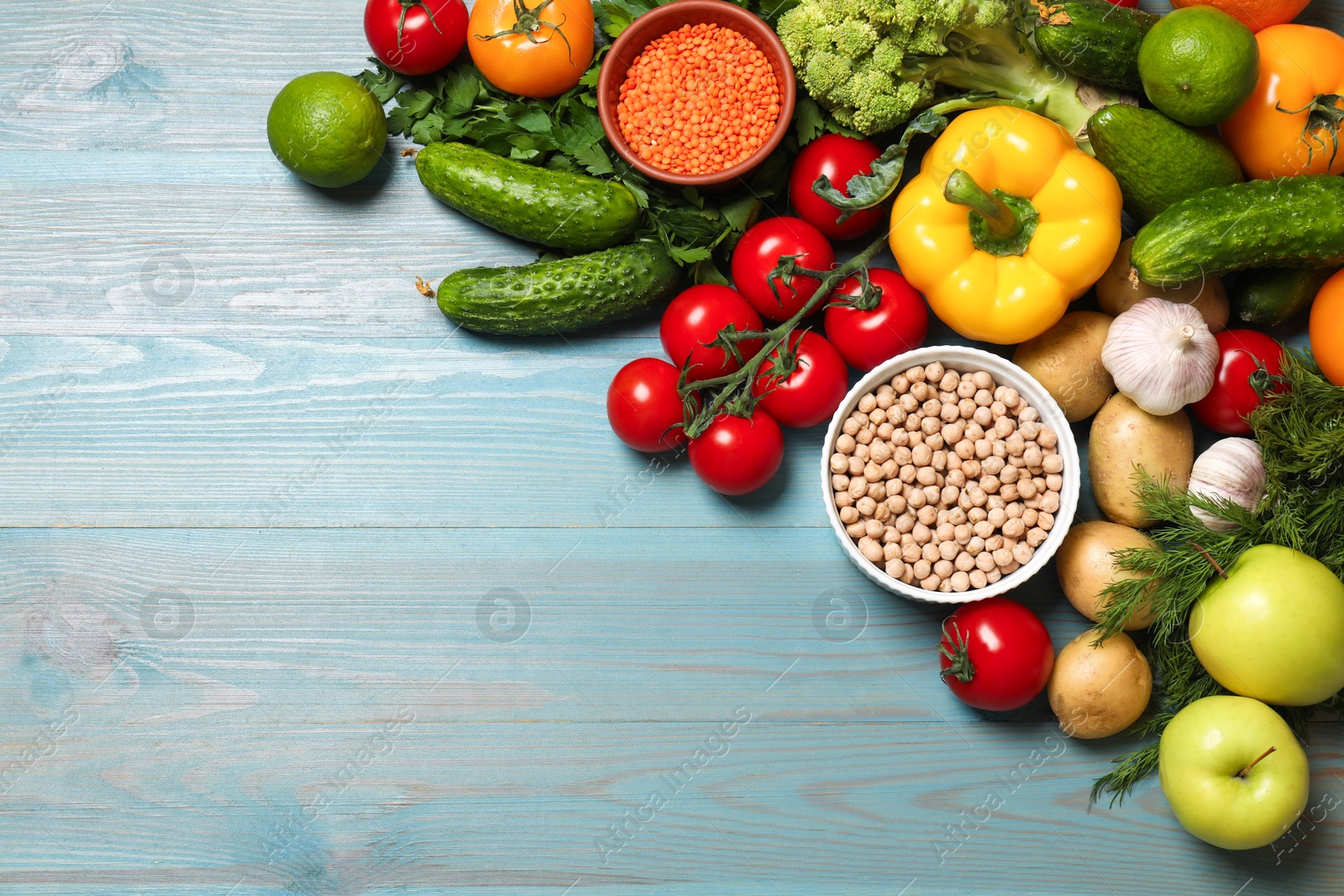 Photo of Different vegetarian products on light blue wooden table, top view. Space for text