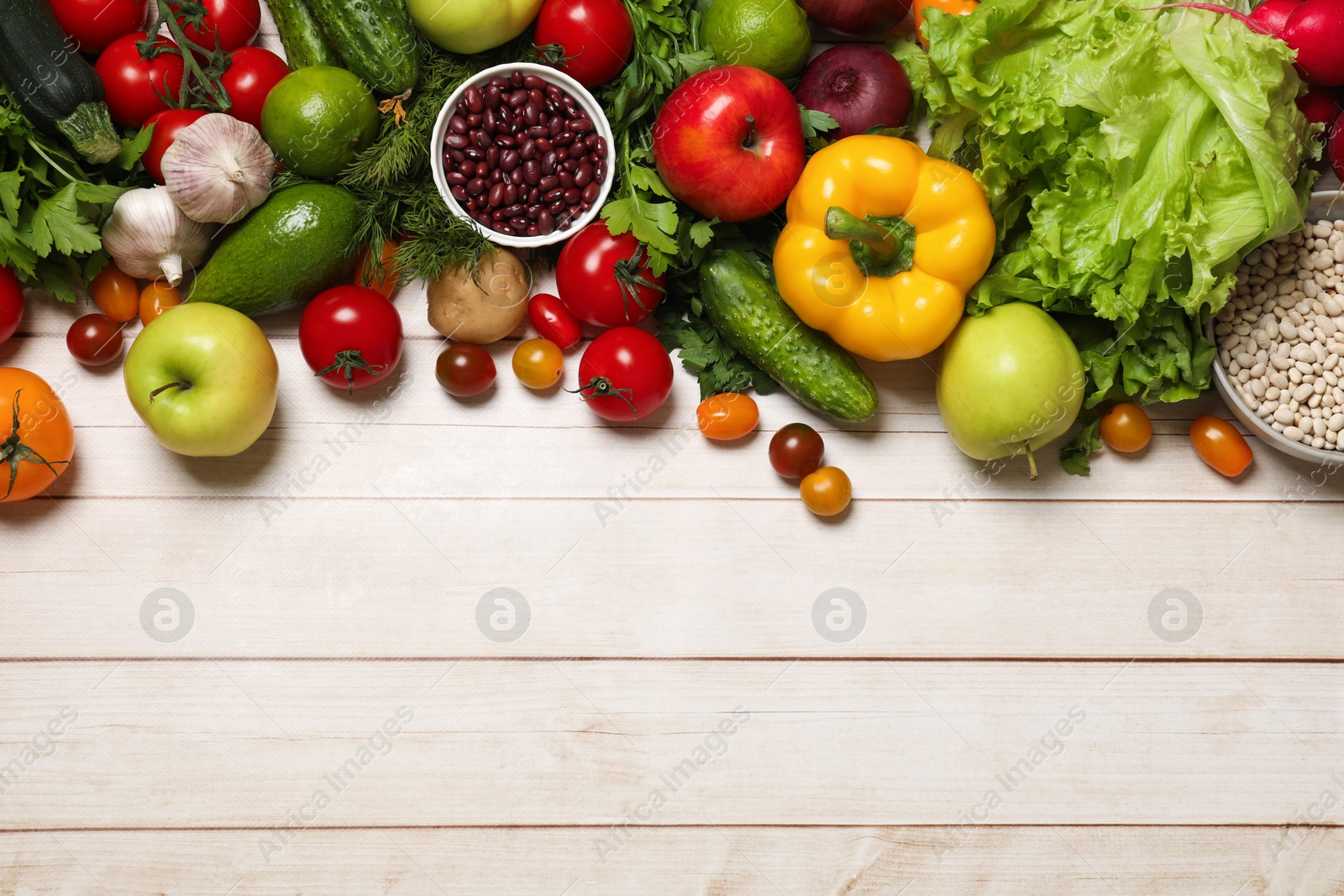 Photo of Different vegetarian products on light wooden table, top view. Space for text