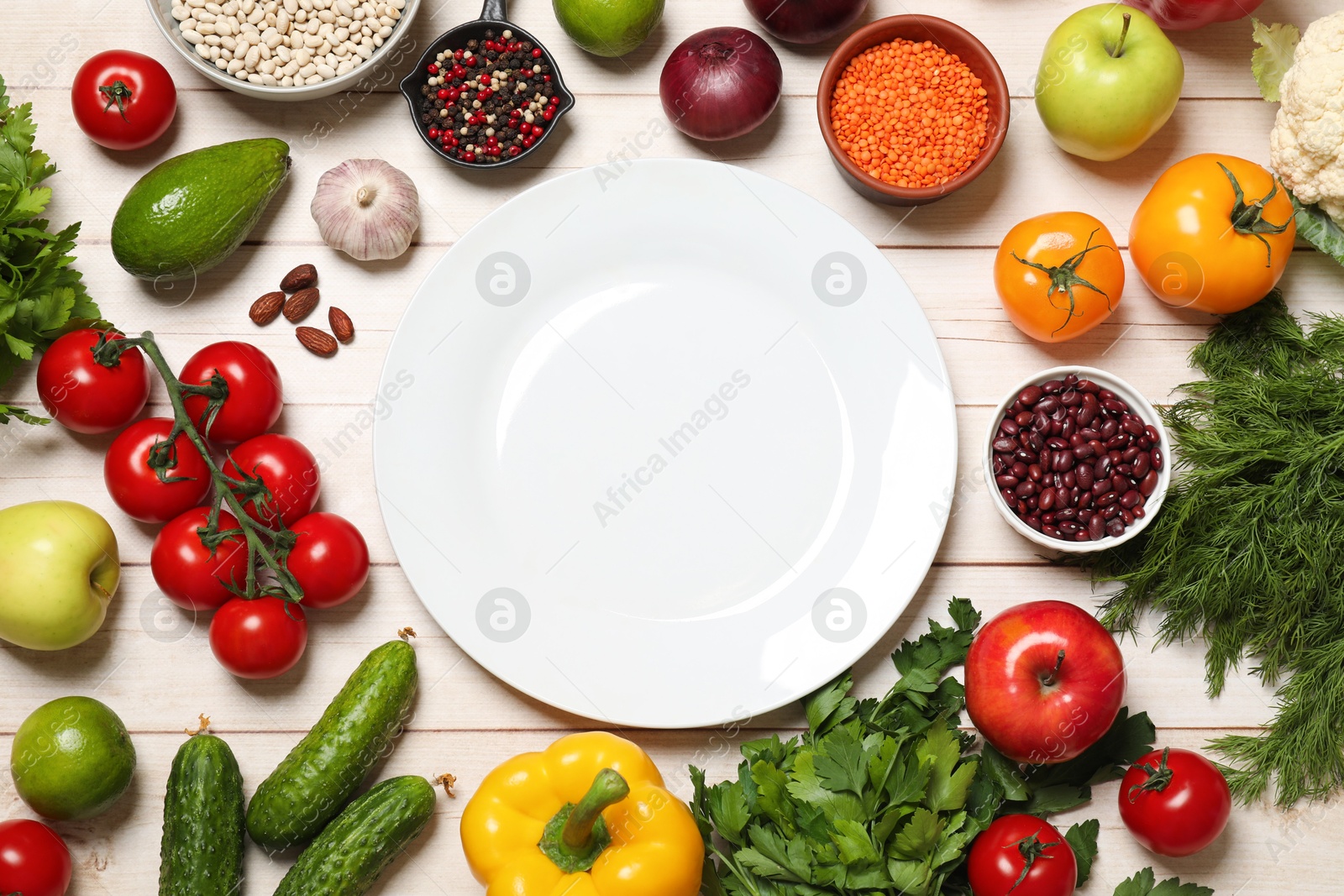 Photo of Different vegetarian products and plate on light wooden table, top view