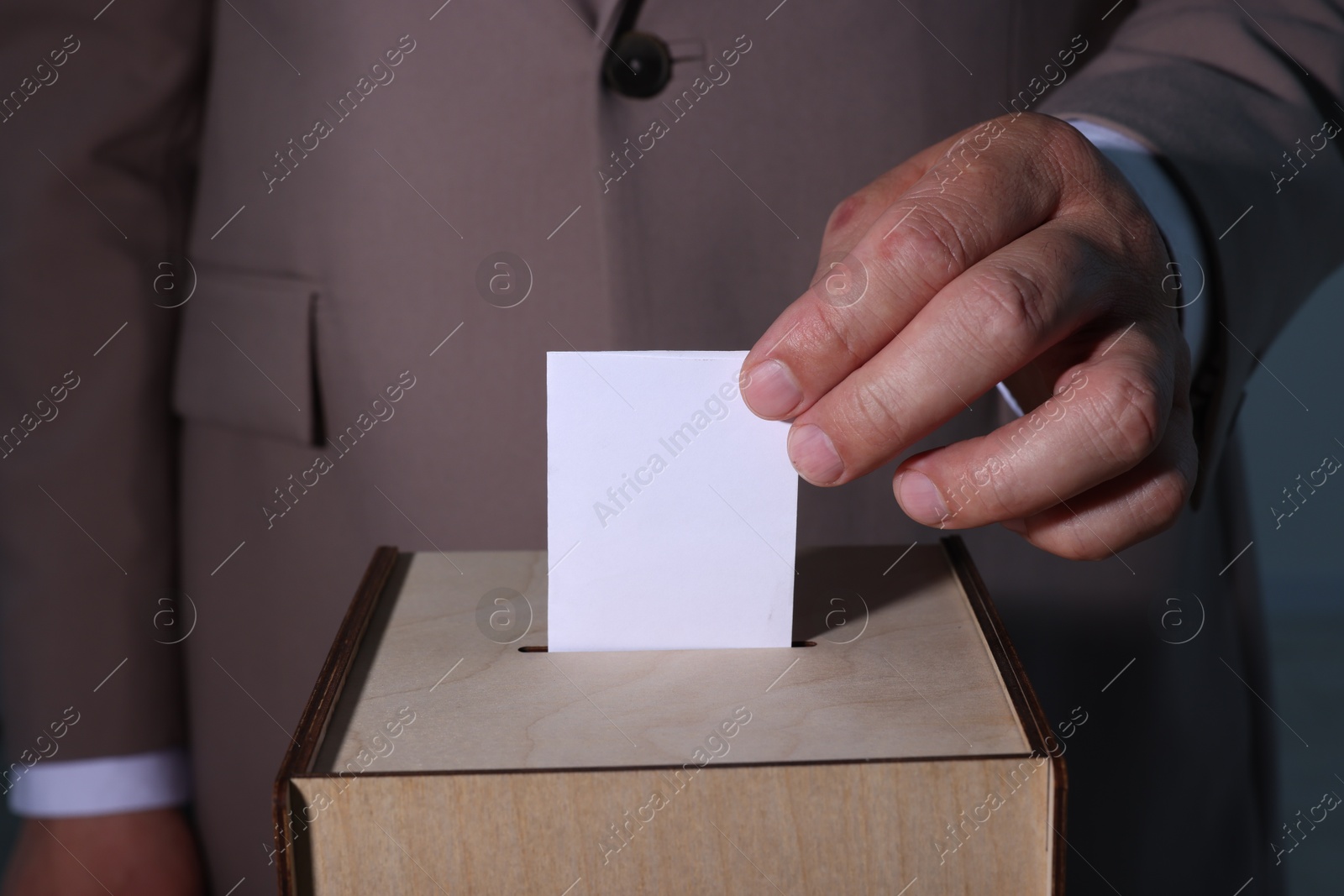 Photo of Man putting his vote into ballot box, closeup