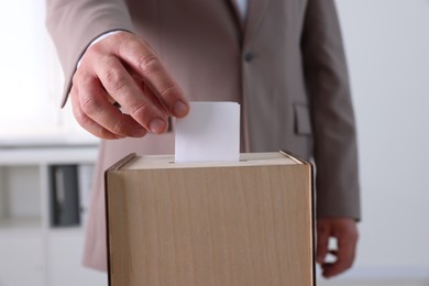 Man putting his vote into ballot box indoors, closeup