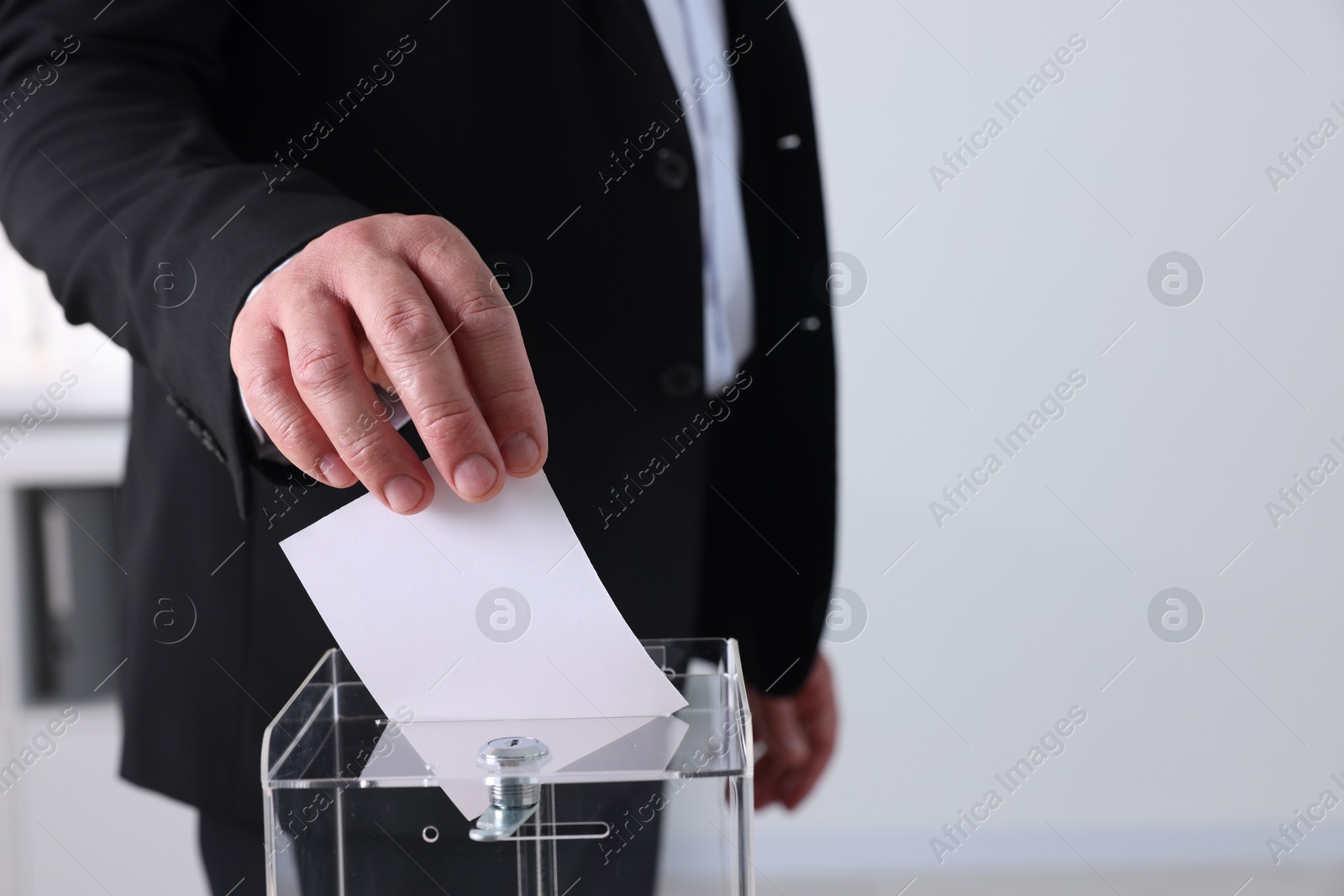 Photo of Man putting his vote into ballot box indoors, closeup. Space for text