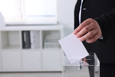 Photo of Man putting his vote into ballot box indoors, closeup. Space for text