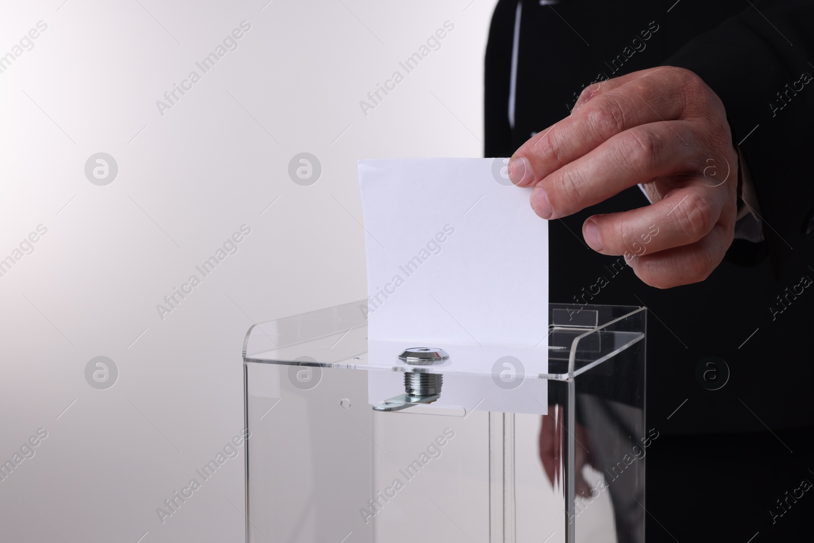 Photo of Man putting his vote into ballot box against white background, closeup