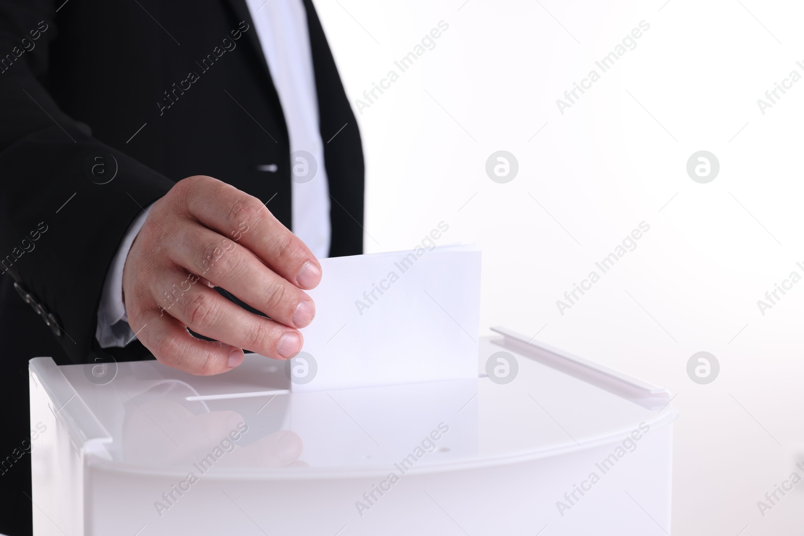 Photo of Man putting his vote into ballot box against white background, closeup