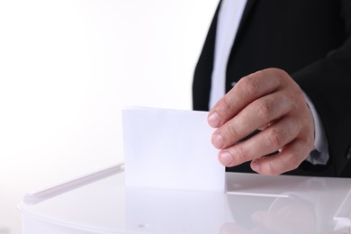 Photo of Man putting his vote into ballot box against white background, closeup