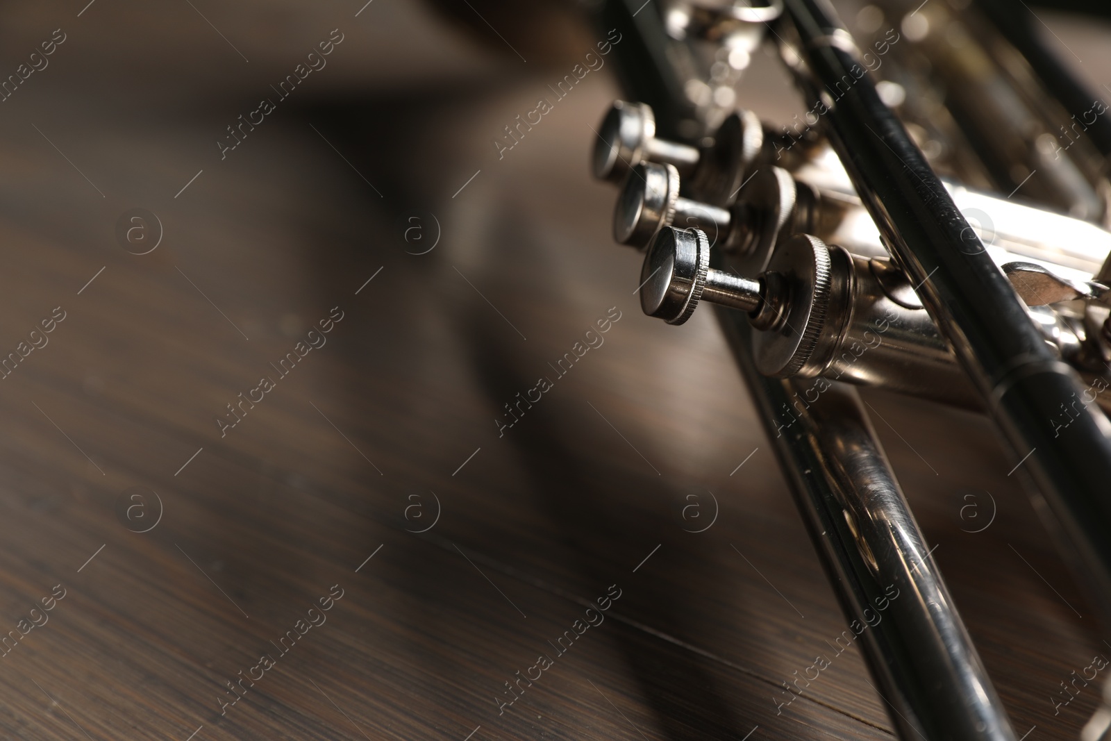 Photo of One trumpet on wooden table, closeup. Space for text