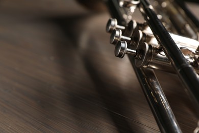 One trumpet on wooden table, closeup. Space for text