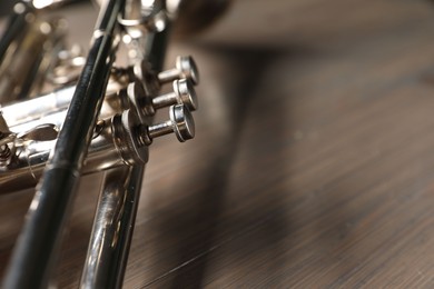 One trumpet on wooden table, closeup. Space for text