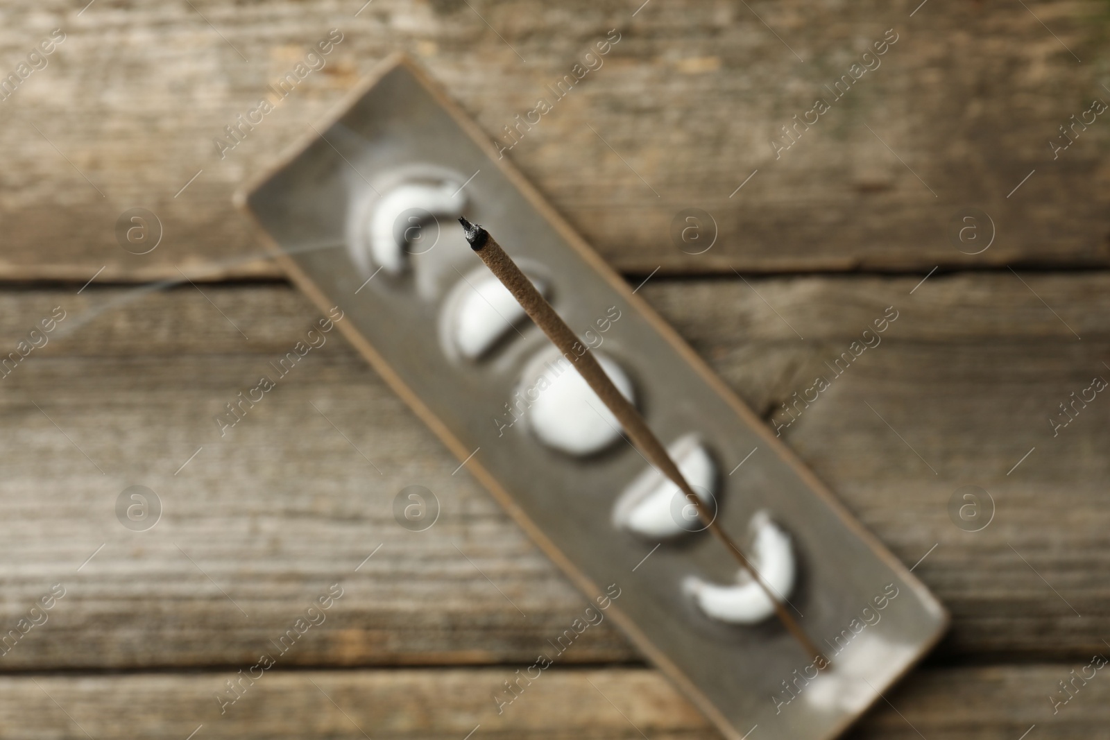 Photo of Incense stick smoldering in holder on wooden table, top view