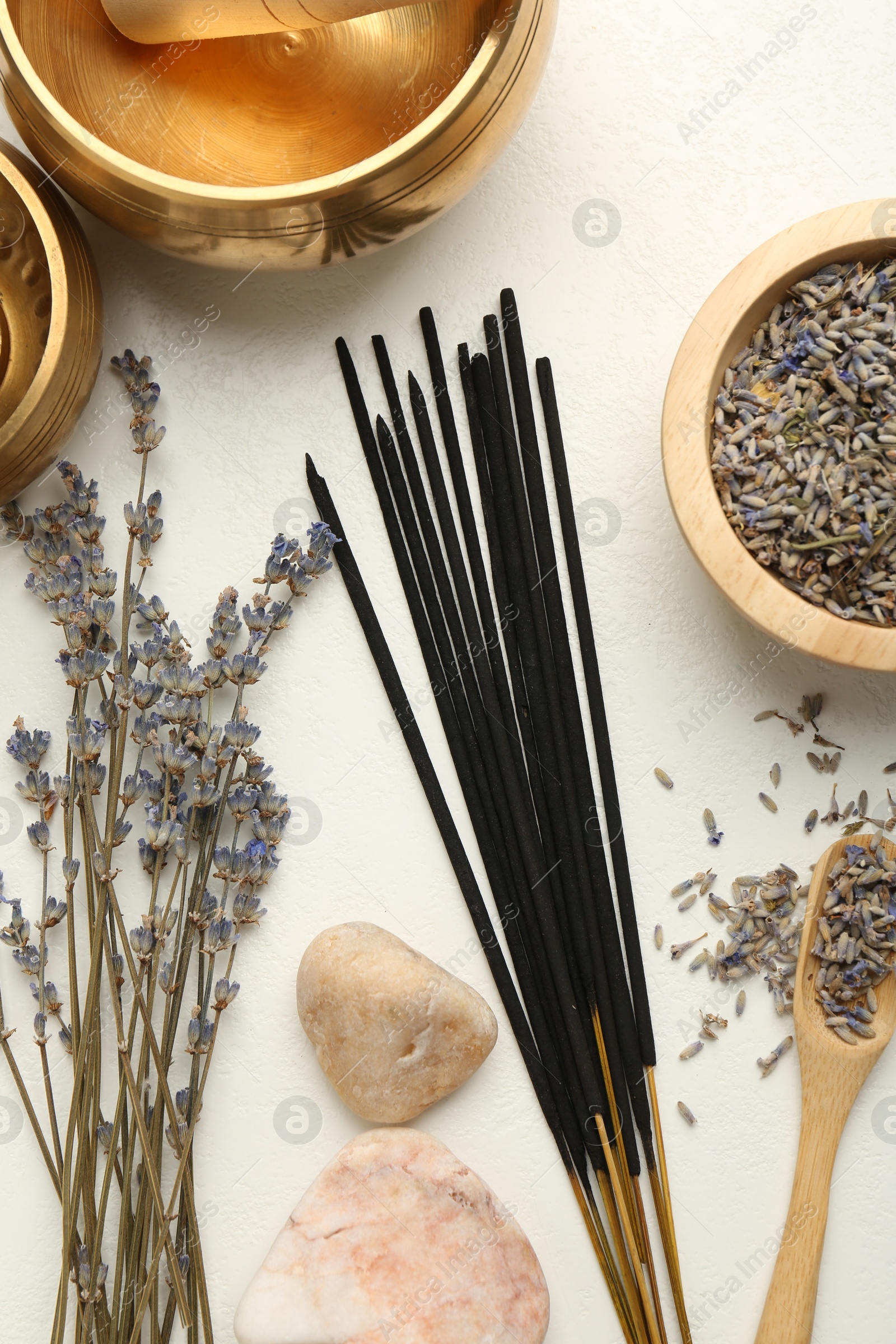 Photo of Incense sticks, Tibetan singing bowls, dry lavender flowers and stones on white table, flat lay