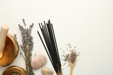 Photo of Incense sticks, Tibetan singing bowls, dry lavender flowers and stones on white table, flat lay. Space for text