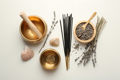 Photo of Incense sticks, Tibetan singing bowls, dry lavender flowers and stones on white table, flat lay