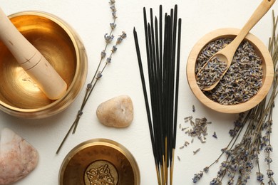 Incense sticks, Tibetan singing bowls, dry lavender flowers and stones on white table, flat lay