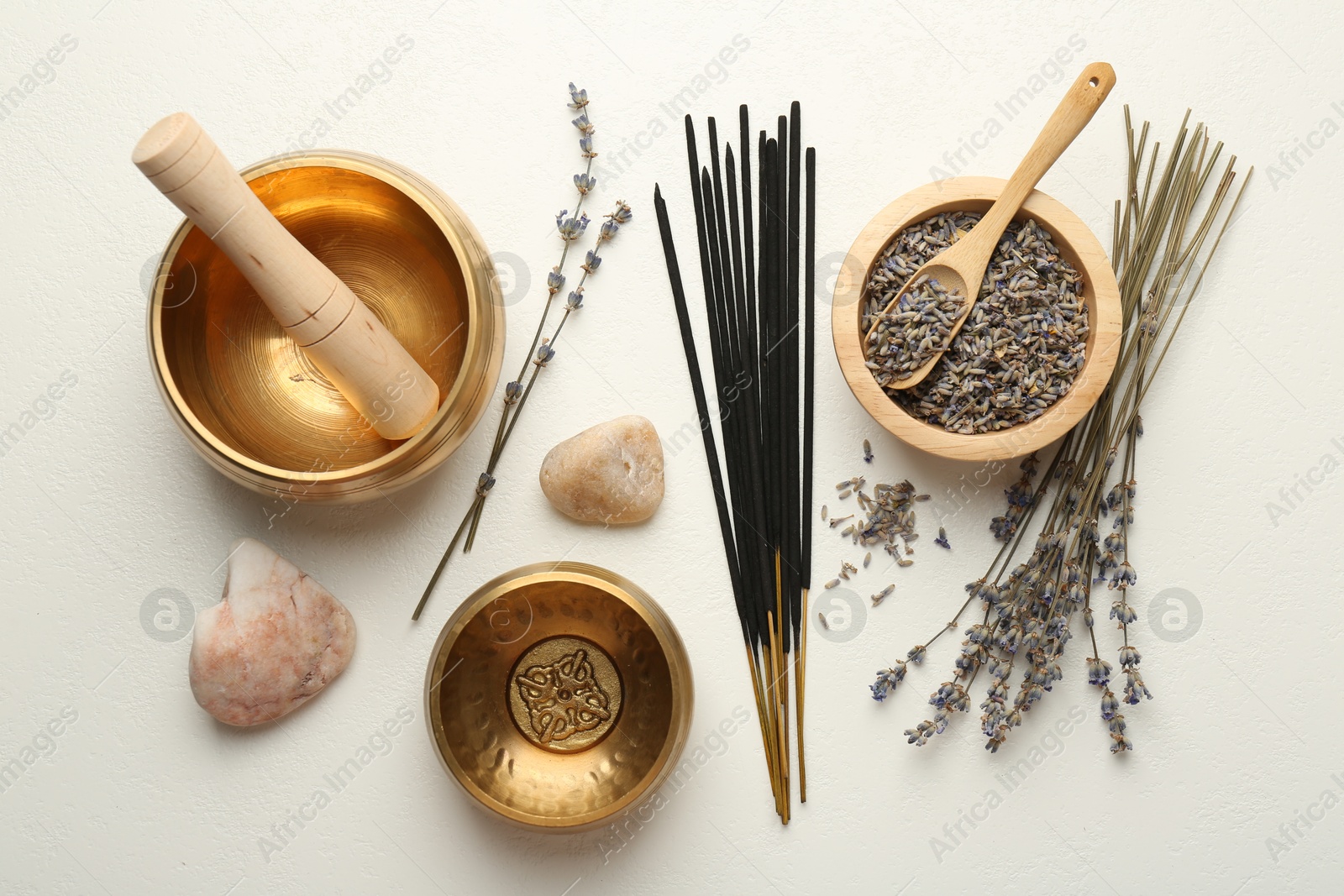 Photo of Incense sticks, Tibetan singing bowls, dry lavender flowers and stones on white table, flat lay