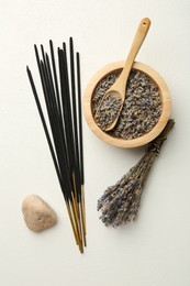 Incense sticks, dry lavender flowers and stone on white table, flat lay