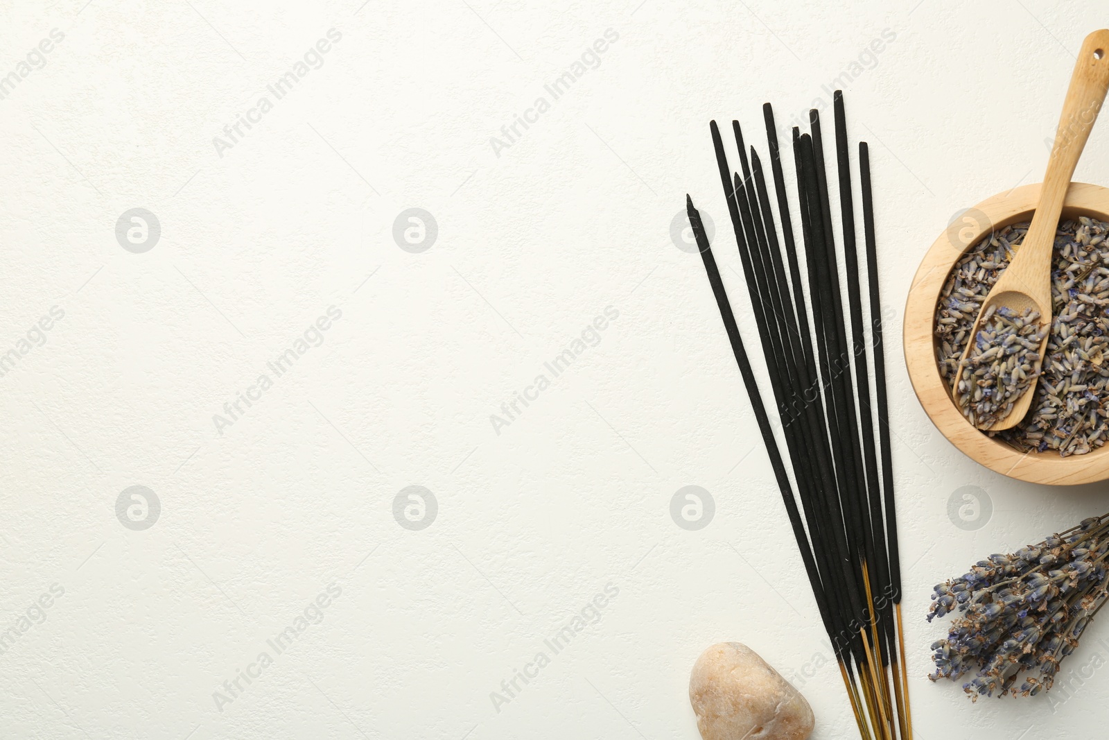 Photo of Incense sticks, dry lavender flowers and stone on white table, flat lay. Space for text