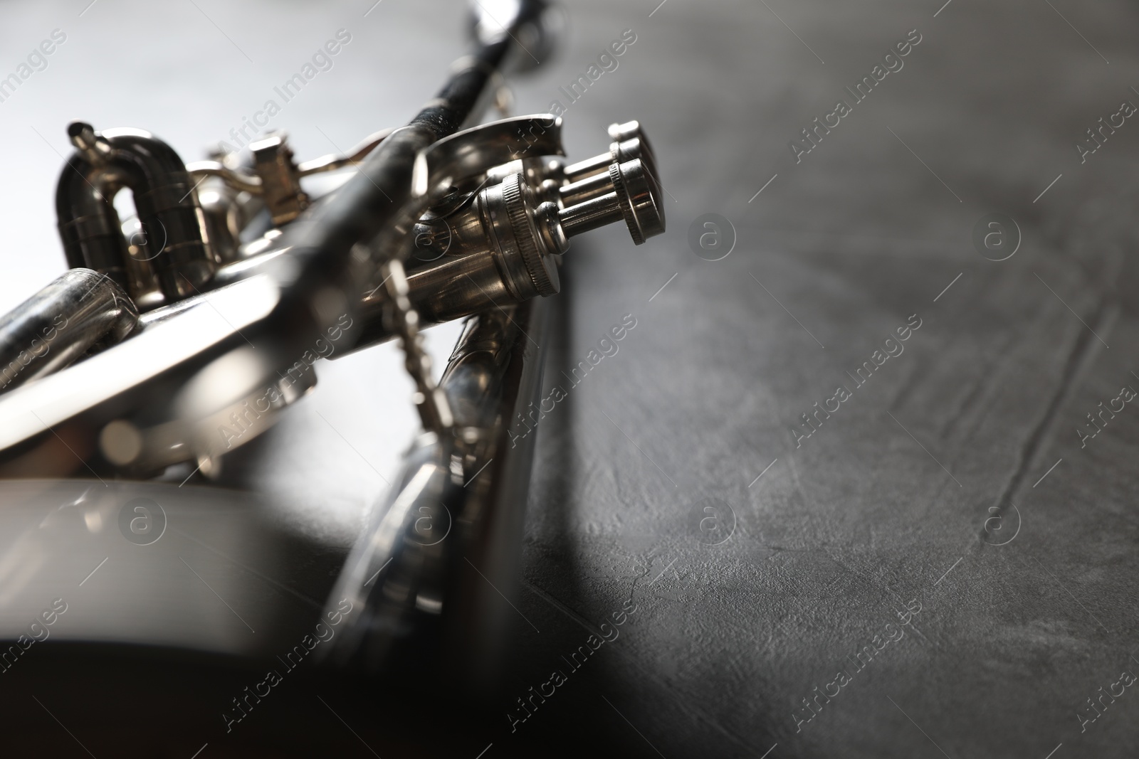 Photo of Closeup view of shiny trumpet on grey textured table, space for text. Wind musical instrument