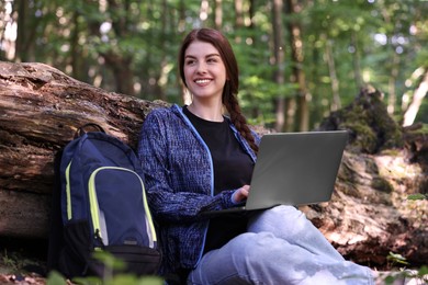 Photo of Smiling freelancer working with laptop in forest. Remote job