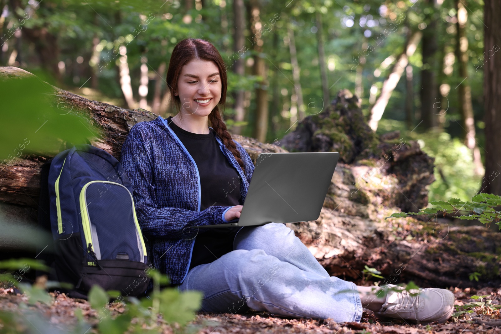 Photo of Smiling freelancer working with laptop in forest. Remote job