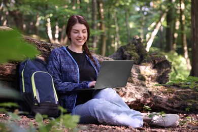 Photo of Smiling freelancer working with laptop in forest. Remote job