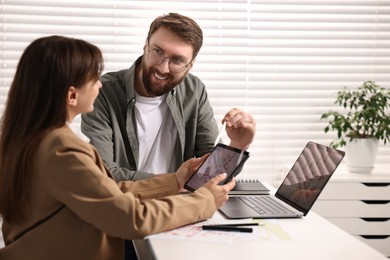 Cartographers working with cadastral map on tablet at white table in office