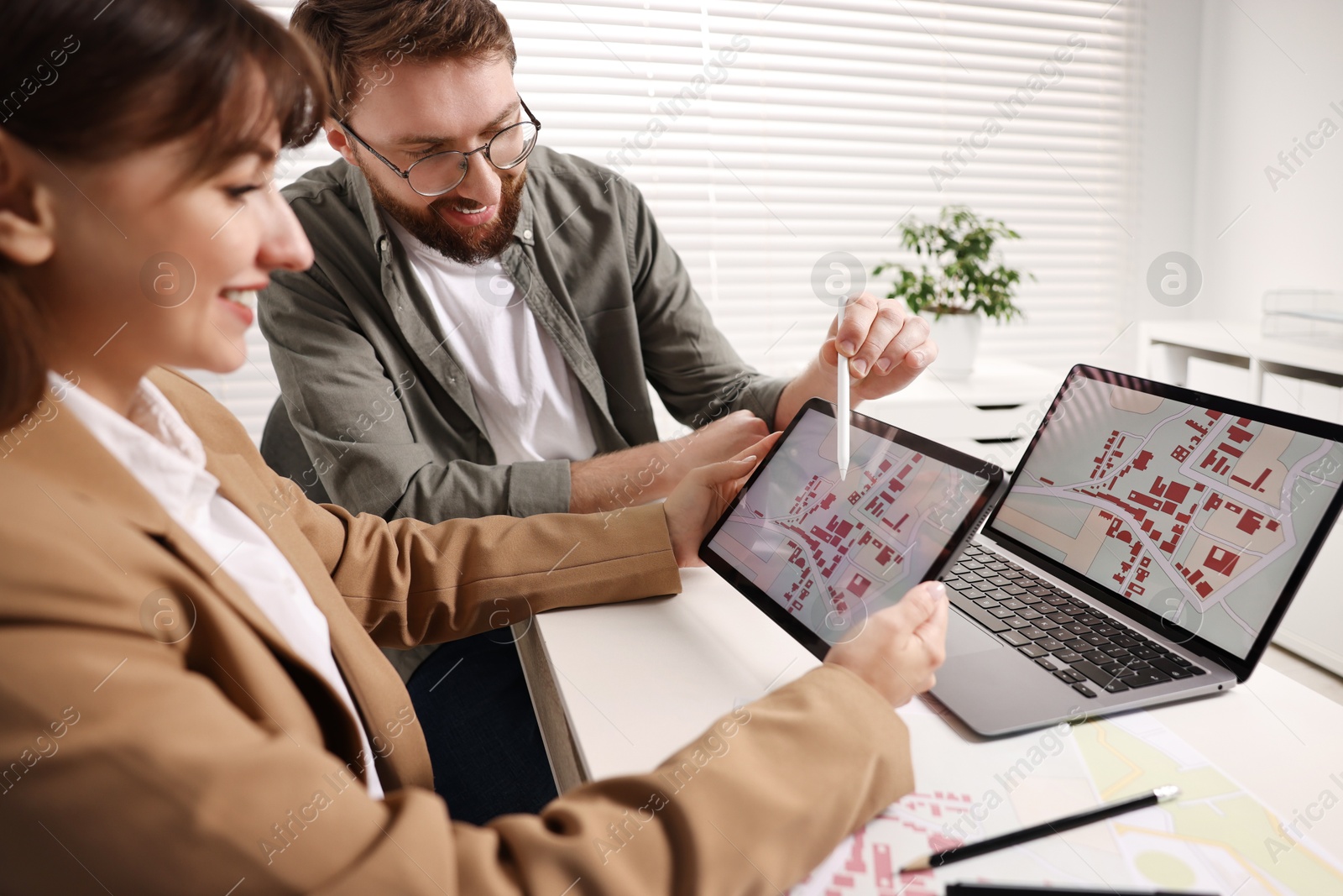 Photo of Cartographers working with cadastral map on tablet at white table in office