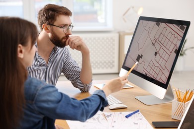 Photo of Cartographers working with cadastral map on computer at table in office