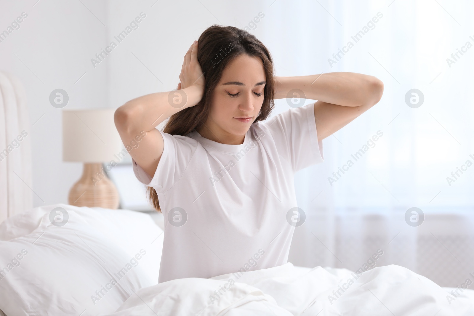 Photo of Woman covering ears in bed at home