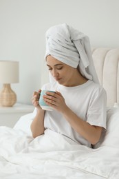 Woman in towel drinking coffee in bed. Good morning