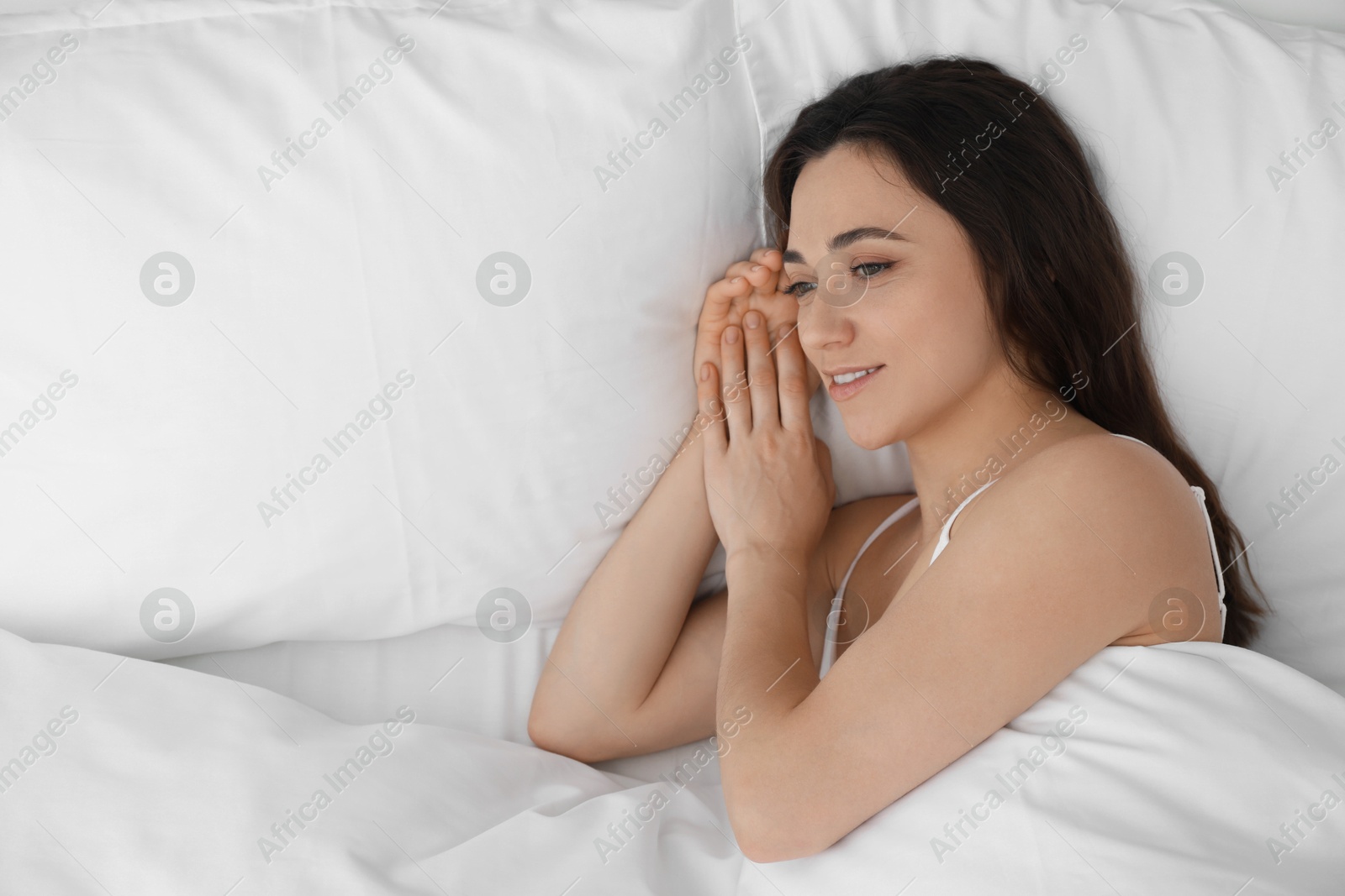 Photo of Smiling woman lying in bed, top view. Space for text