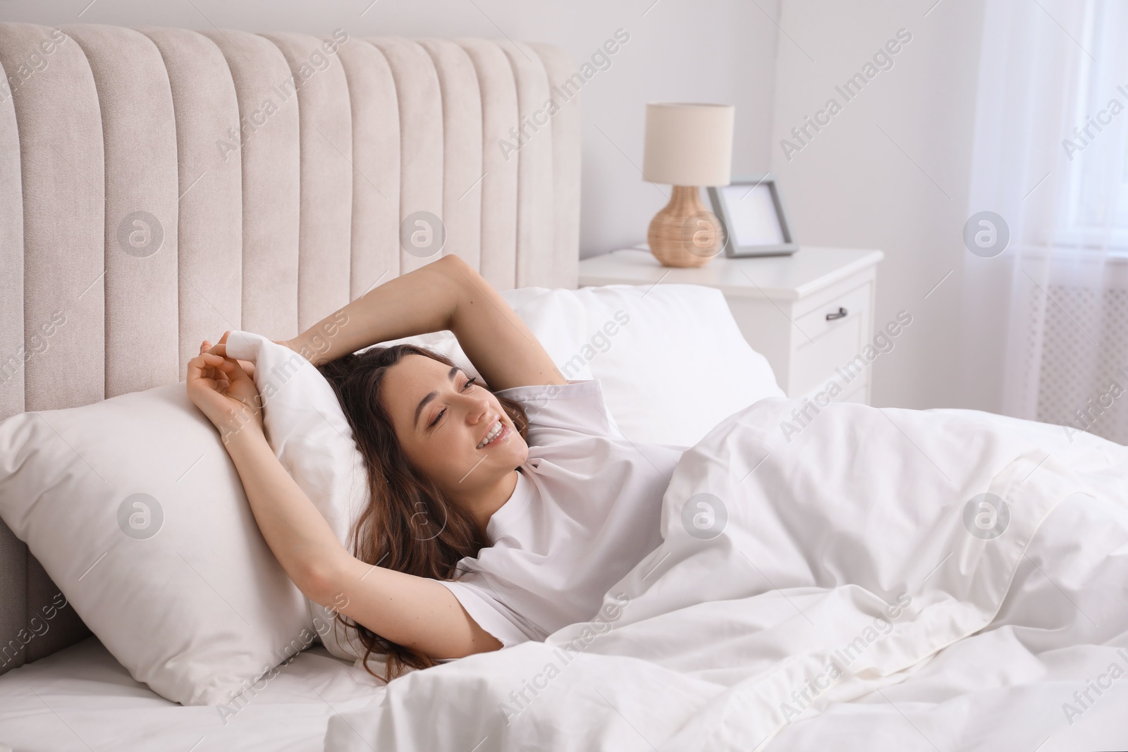 Photo of Happy woman lying in bed at home