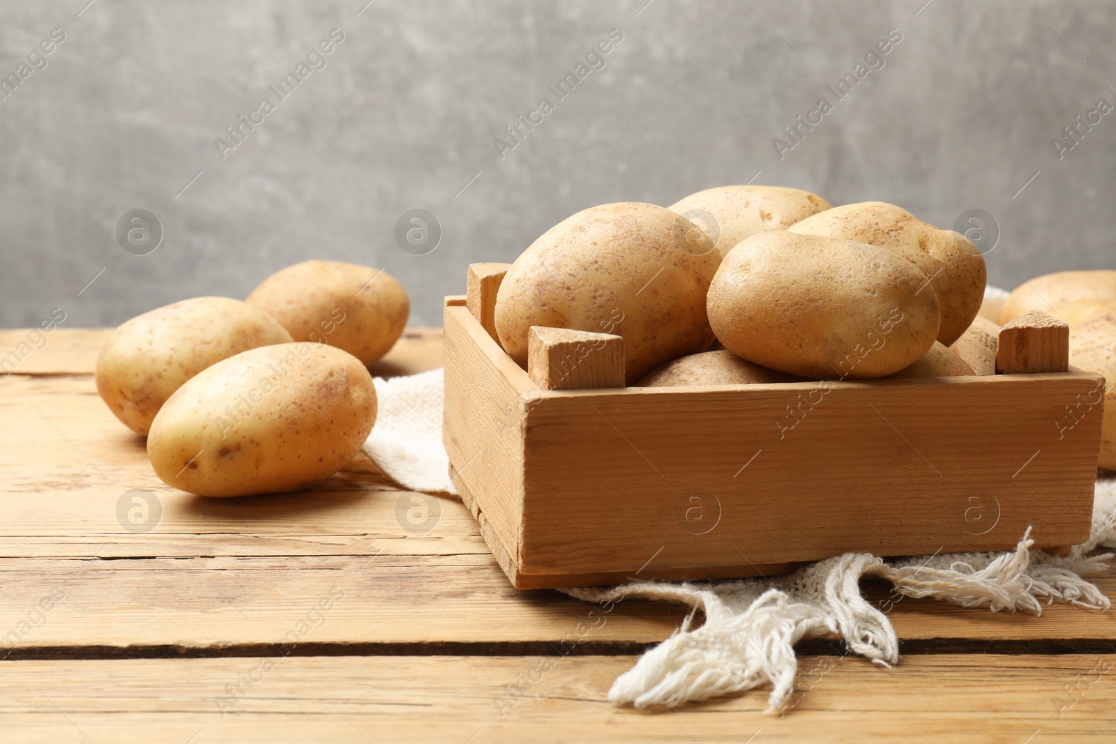 Photo of Many fresh potatoes in crate on wooden table