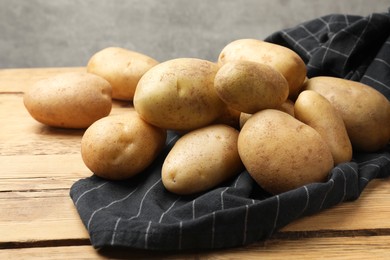 Photo of Pile of fresh potatoes on wooden table, closeup