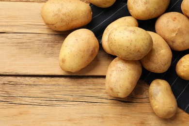 Photo of Many fresh potatoes on wooden table, top view. Space for text