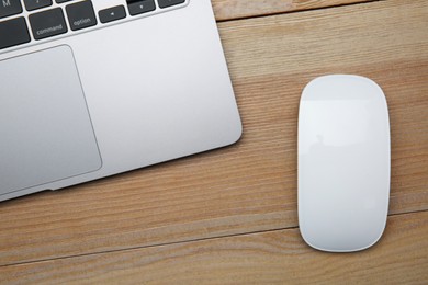 Wireless mouse and laptop on wooden table, top view