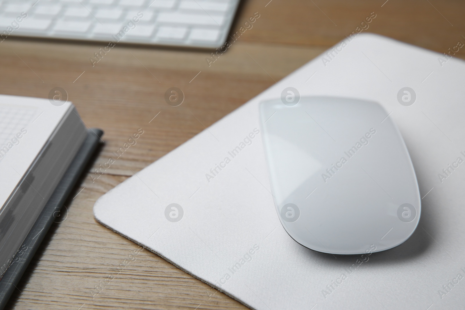 Photo of Wireless mouse with mousepad on wooden table, closeup