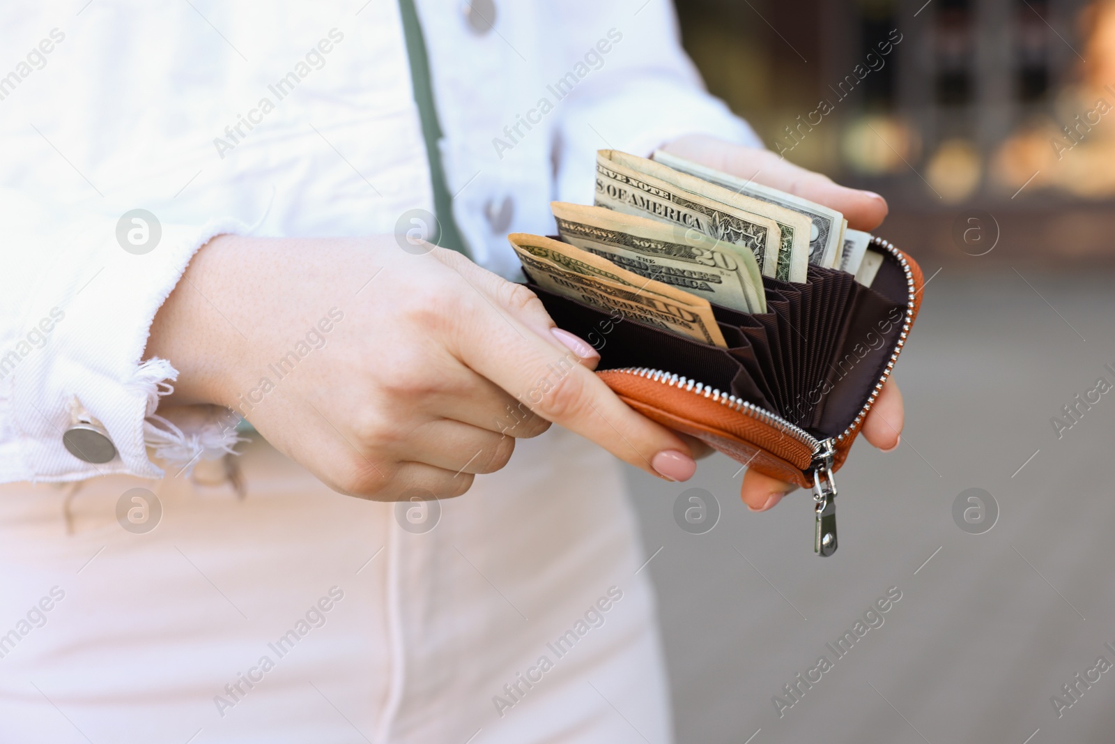 Photo of Woman holding purse with banknotes outdoors, closeup