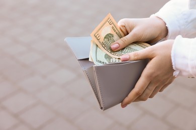 Woman holding purse with banknotes outdoors, closeup